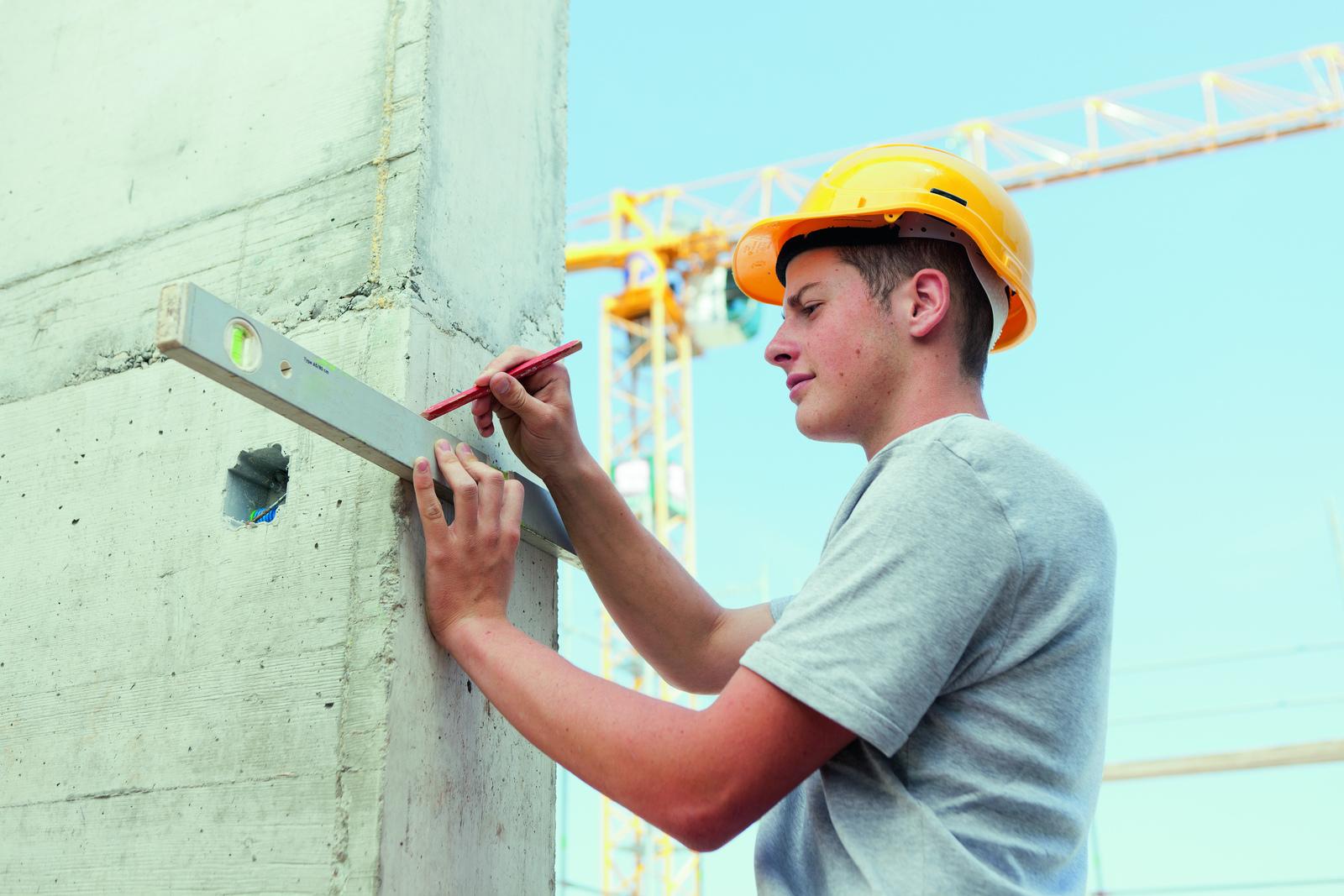 Apprenti effectuant un traçage au niveau sur un mur
