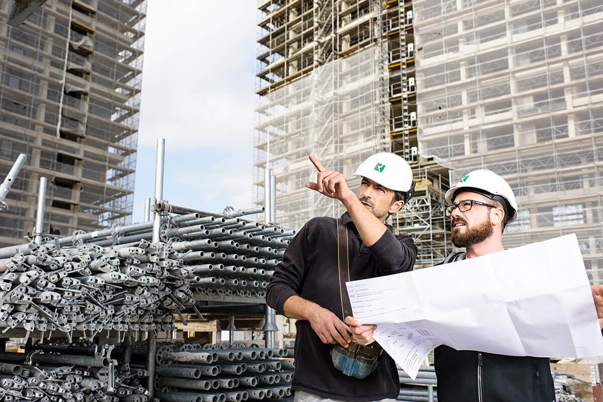 Conducteur de travaux et collaborateur étudiant un plan sur un chantier