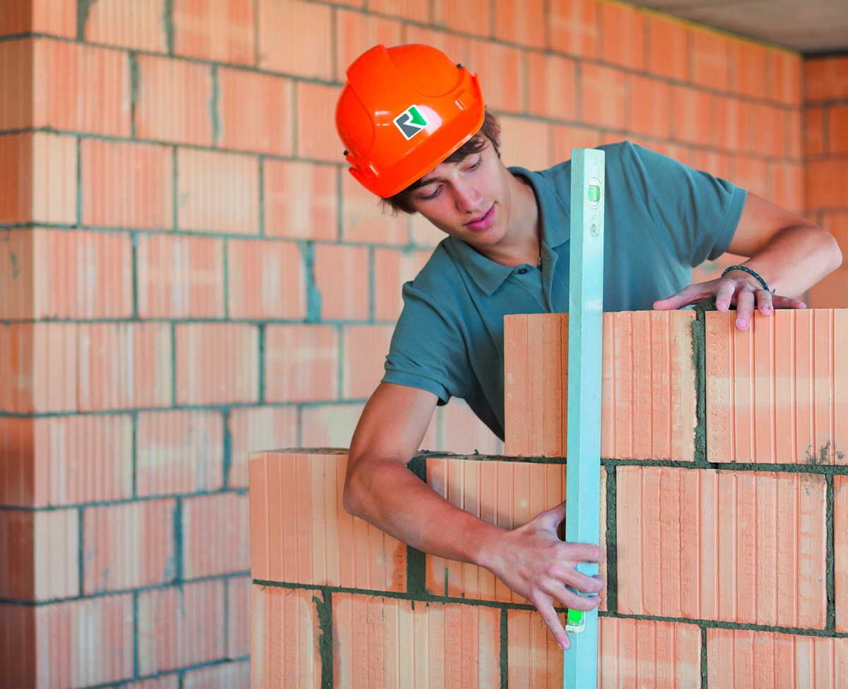 Apprenti maçon montant un mur en briques