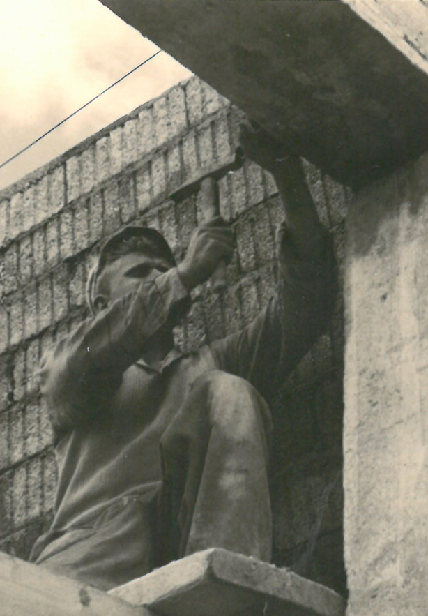 Maçon montant un mur en briques, photo d'archives